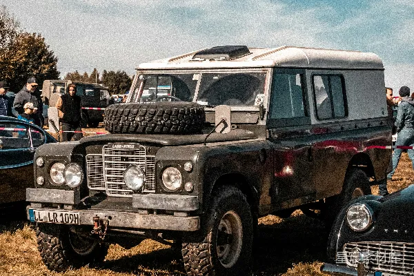 vintage路虎 Defender停在草地上方的空地上。
