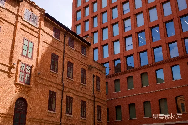 高清摄影 在老旧砖砌建筑和现代砖砌建筑之间的庭院中的人们。