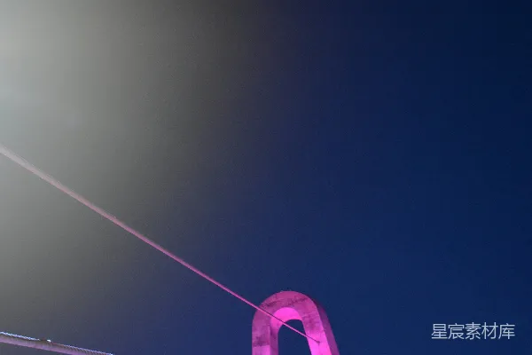 夜幕下一轮弯月高悬在粉色拱桥之上。