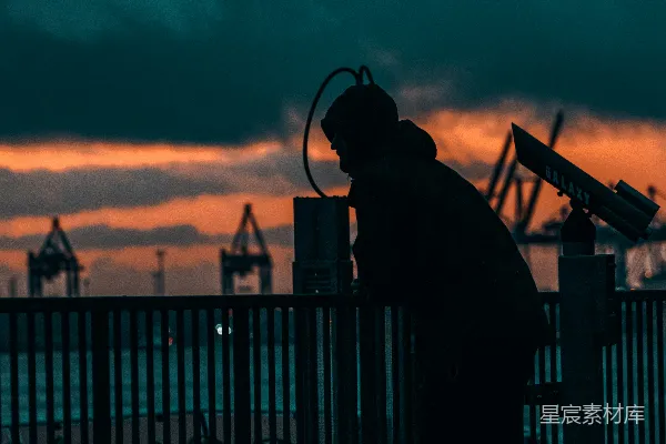 高清摄影 夕阳下，一个男人站在铁栅栏旁边的身影。