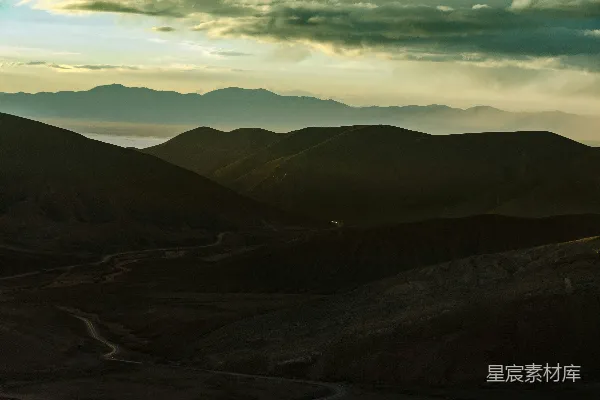 山峦下积云间草原的全景摄影