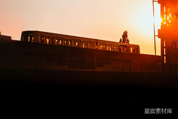 高清摄影 一列火车在夕阳下经过一座高楼。