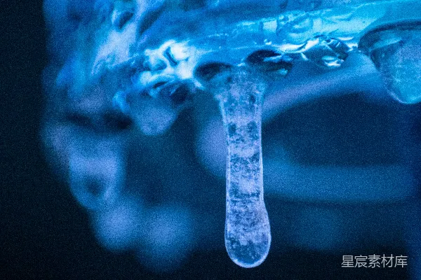 高清摄影 一束蓝色灯光下，一挂滴水的冰柱特写。