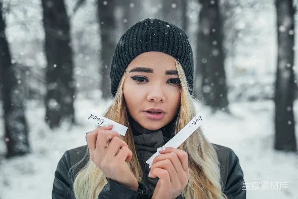 高清摄影 穿着黑色针织帽和灰色夹克的女人手里拿着一张白色打印机纸。
