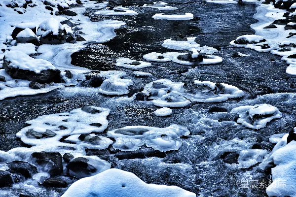 高清摄影 一条河流，岩石上覆盖着雪，水中流淌着水。