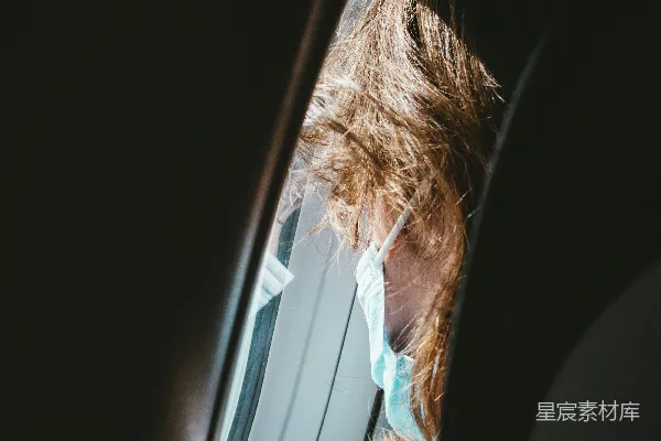 戴着口罩的女人望着窗外。