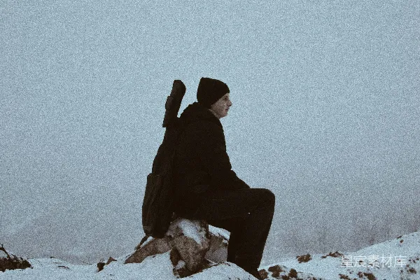 高清摄影 坐在棕色石头上，周围覆盖着雪的男子。