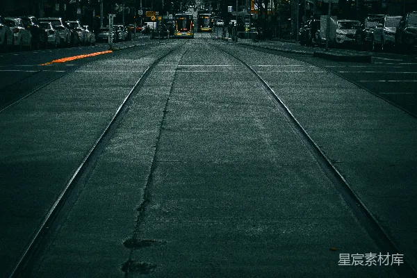 城市街道上的有轨电车轨道旁有建筑和树木。