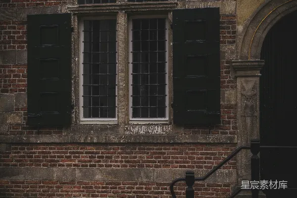 旧砖砌建筑，有深色的百叶窗和窗户。