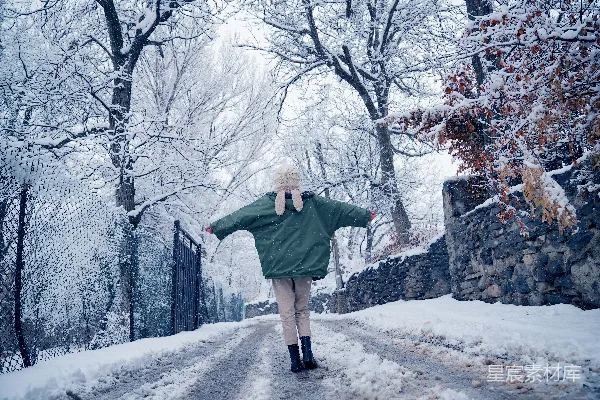 高清摄影 一个女人走在积雪覆盖的小路上。