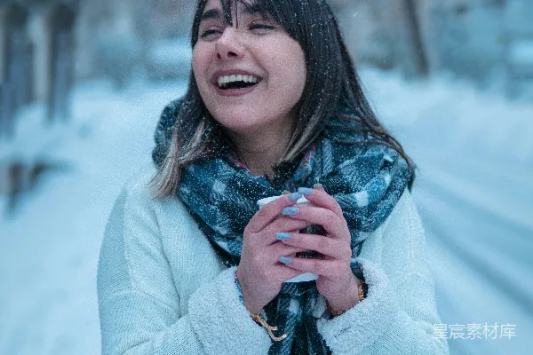 高清摄影 一个女人站在雪地里，脖子上围着围巾。