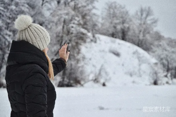 高清摄影 一个女人站在雪中看着她的手机。
