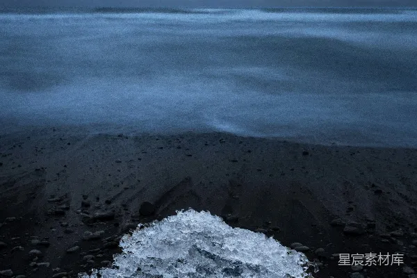 高清摄影 冰块在黑色沙滩上，海浪拍打着岸边。