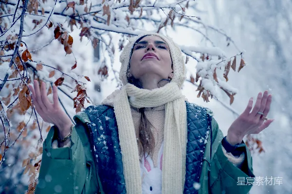 高清摄影 一位女士站在一棵被雪覆盖的树前。
