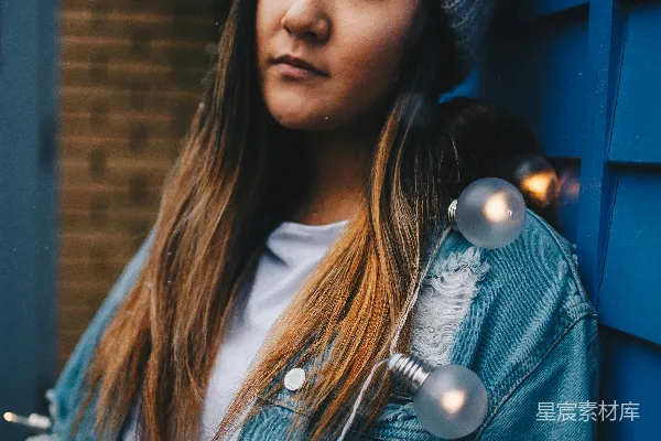 妇女戴着灰色针织帽倚靠在蓝色木墙上