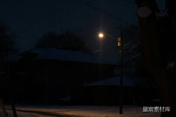 夜晚雪地上的道路被街灯照亮。