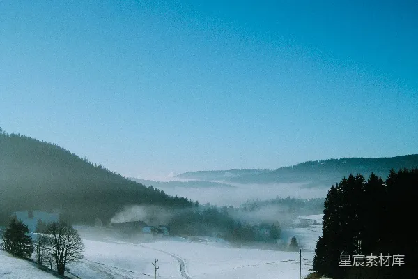 高清摄影 一片覆盖着雪的田野，背景中有树木和山脉。