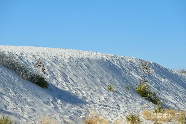 一片覆盖着白雪的山坡和蓝天下的绿色草地