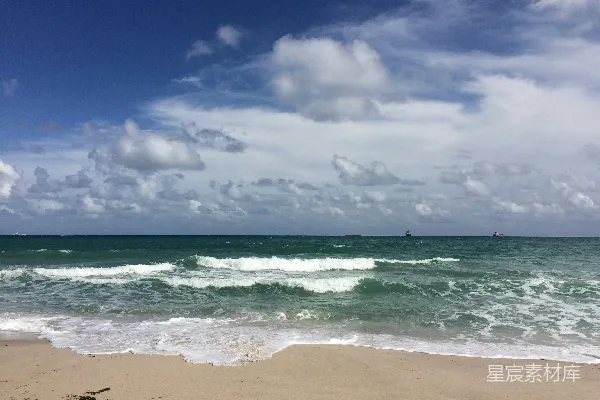 海浪在蓝天白云的背景下拍打着岸边，在白天