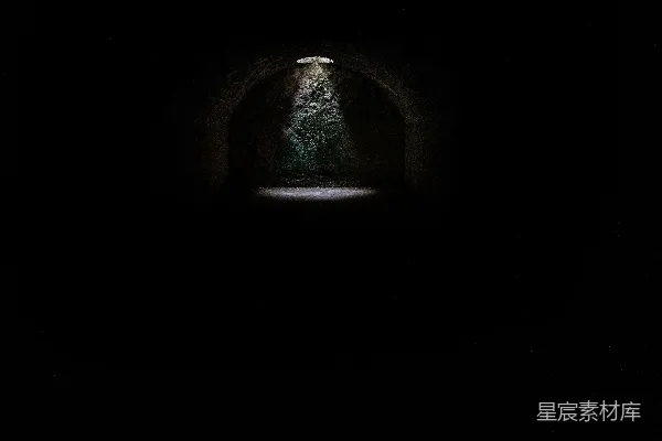 高清摄影 一座暗黑的米诺斯地下洞穴中，一个洞口投射出一束聚光灯。