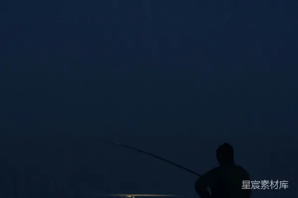 高清摄影 一个男人在夜间在海滩上钓鱼。