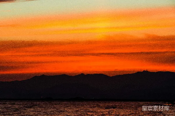 暗山与水面映照着一片炽烈的橙色夕阳