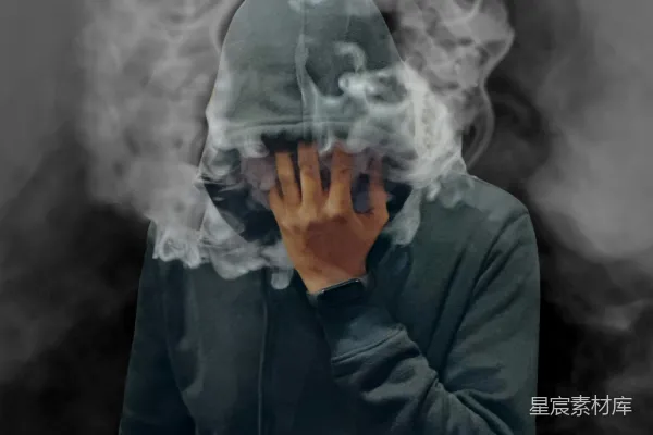 高清摄影 一个穿着连帽衫的男人用烟遮住了脸。
