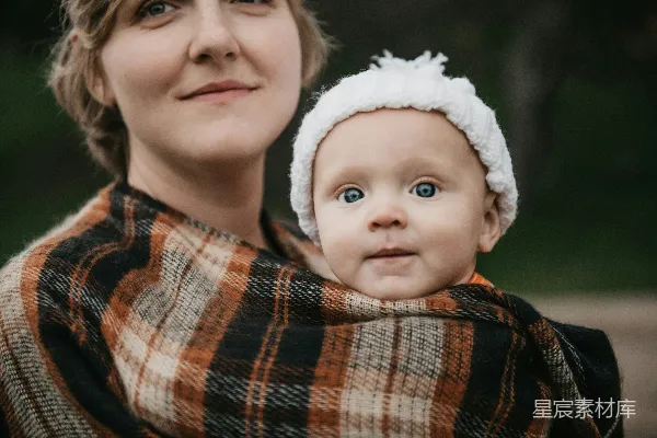 一个女人抱着一个裹着毯子的婴儿