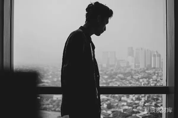 一个男子的侧影凝视着窗户外面。