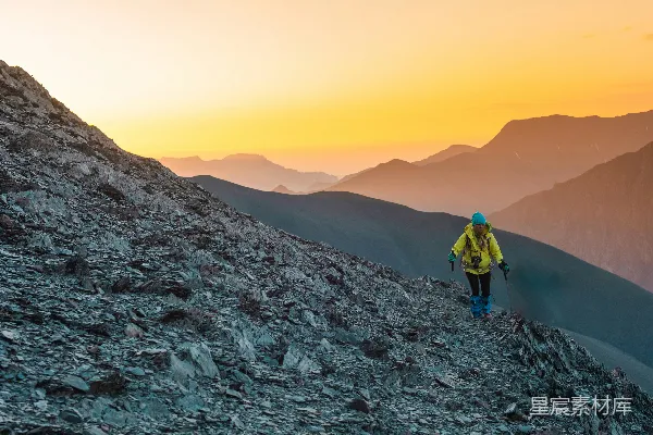 一个男子在夕阳下攀登高山。