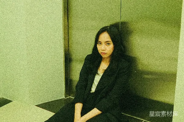 黑色风衣和黑色长裤的女人坐在白色地砖上