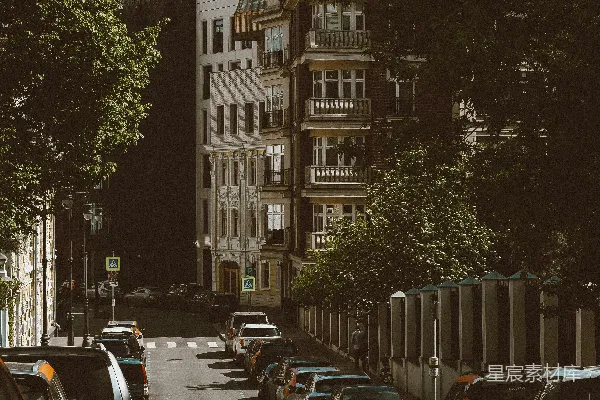 一条窄街两旁停着汽车，两侧是历史建筑。