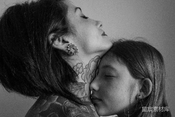颈部有纹身的女人正抱着一个年轻女孩。