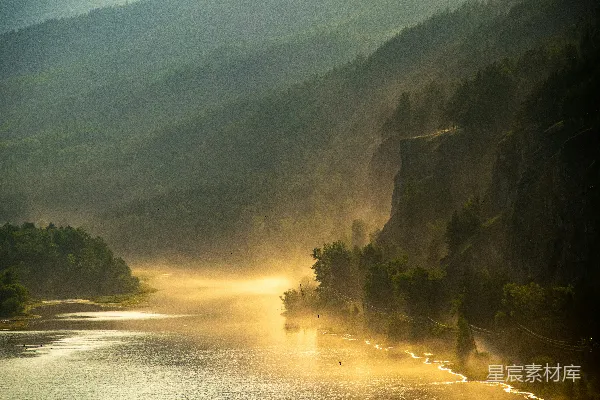 雾气弥漫的河流穿行于森林覆盖的山间谷地。