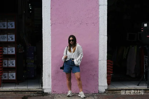 女人站在一座粉色建筑的前面。