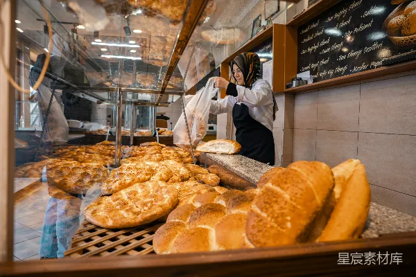 贝克在面包店展示柜中整理新鲜出炉的面包。
