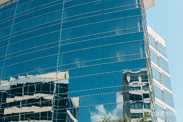 高清摄影 一座大型玻璃建筑，前面有树木。