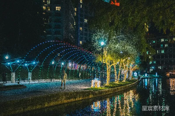 高清摄影 一个男人在夜晚沿着河边的街道行走。