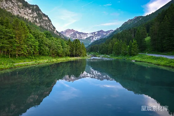 近湖傍山的绿树与蓝天白云下的景色在白天。