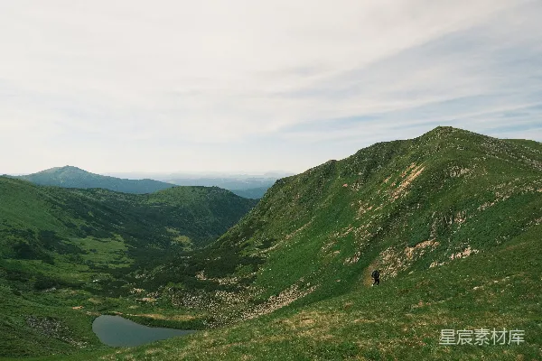 草坡上俯瞰一片宁静山谷和湖泊。