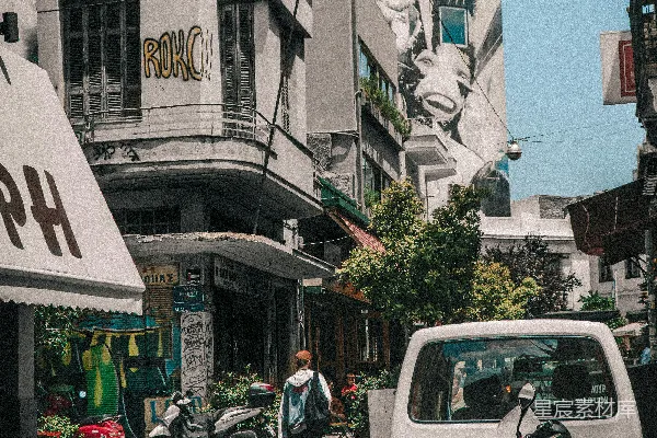 一辆卡车沿街行驶，旁边是高大的建筑物。