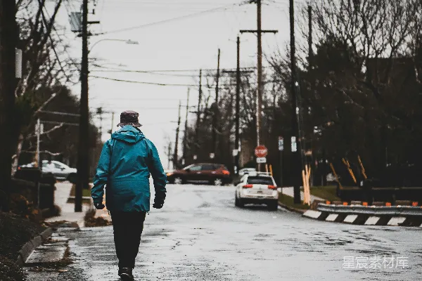 穿着蓝夹克的男人在雪覆盖的小路上白天行走