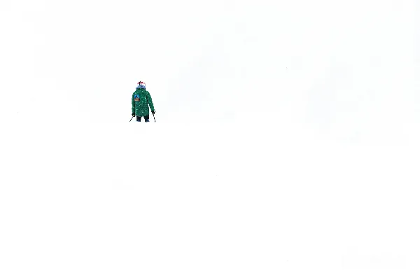 穿着绿色外套的人在一片雪景中行走