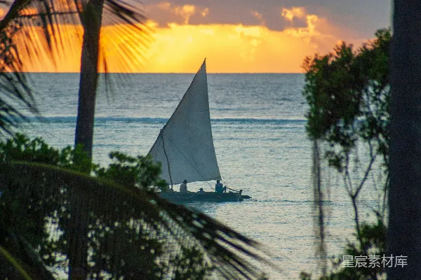夕阳下的白帆船在海面上
