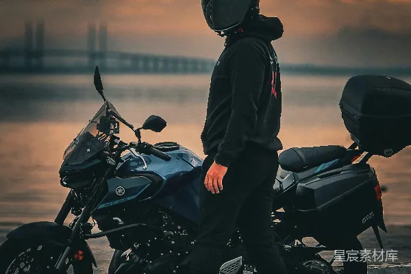 一个男人站在一辆摩托车旁边，靠近一个水域。