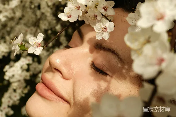 闭着眼睛的女人被白色的花朵环绕着。