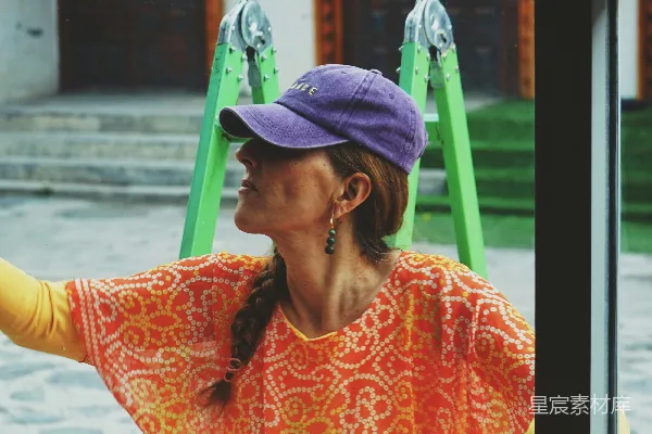 一个女人戴着紫色帽子望着窗外。