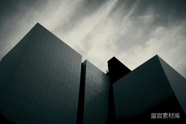 暗色的棱角分明的现代建筑矗立在一片戏剧性的阴云密布的天空下。