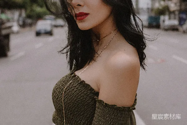 绿色上衣露肩的女人在白天站在路上