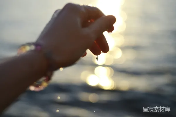 夕阳下手戴彩色手链滴水的手掌。